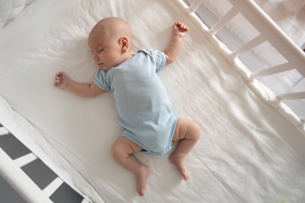 baby in blue clothing in a white crib